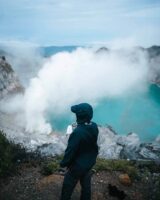 kizzi facing the crator at mount ijen with the blue acidic lake and a slupher cloud